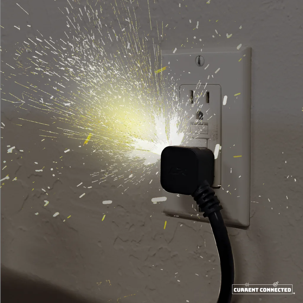 Photo of a cord plugged into an outlet and shooting sparks. 